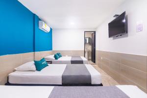 圣玛尔塔Hotel Cuchara de Palo Ayenda的客房设有三张床和一台平面电视。