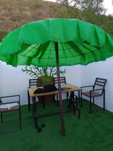 MacaelCasa rural Mccoy的绿伞下的桌椅