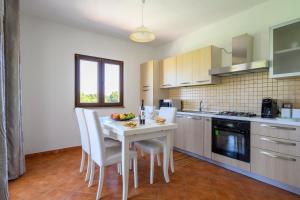洛特佐拉伊6 - Meraviglioso appartamento con terrazza - Sa Crai Apartments Sardinian Experience的厨房配有白色的桌椅和柜台。