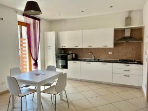 阿科Appartamento Maso Giare的厨房配有白色橱柜和桌椅