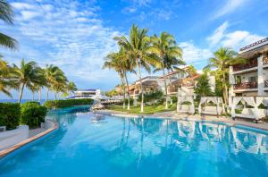 莫雷洛斯港Desire Riviera Maya Pearl Resort All Inclusive - Couples Only的棕榈树和建筑的度假村游泳池