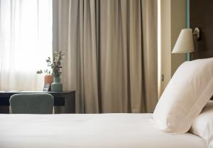 潘普洛纳AZZ Pamplona Norte Hotel的一间卧室配有一张床、一张书桌和一个窗户。