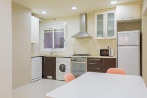 巴塞罗那阿尔卡姆金色公寓的一间厨房,配有白色家电和桌椅