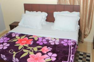 恩德培Alice Gardens & Campsite的一张带紫色和白色毯子及枕头的床