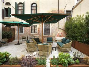 威尼斯Palazzo Keller的庭院配有桌椅和遮阳伞。