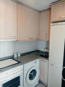 韦斯卡Acogedor apartamento con piscina y garaje的厨房配有白色橱柜和洗衣机。