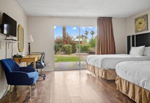 棕榈泉Sol Springs Inn的酒店客房设有两张床、一张书桌和一个窗户。