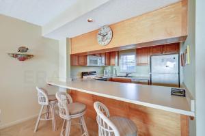 费南迪纳比奇阿米莉亚南 - B4公寓的厨房配有带凳子的柜台和墙上的时钟