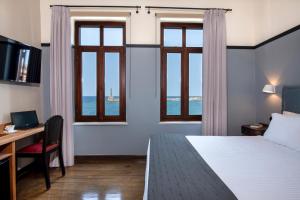 干尼亚Mosaic Venetian Harbour Suites的酒店客房设有一张床、一张书桌和窗户。