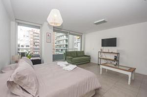布宜诺斯艾利斯Libertador Complete Suite的白色卧室配有床和绿色沙发