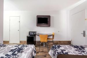 佩科斯Rodeo Inn的一间卧室配有一张桌子和一台墙上的电视。