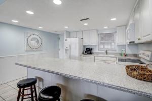 费南迪纳比奇Striking Oceanview Condo的厨房配有白色橱柜和带凳子的台面