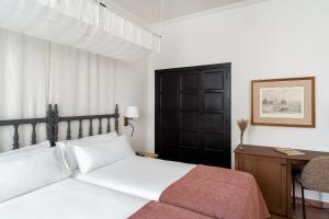 罗德里戈城罗德里戈城市旅馆的卧室配有白色的床、书桌和床罩