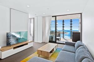 纽卡斯尔Exceptional Beach views - Luxury apartment的客厅配有蓝色的沙发和电视