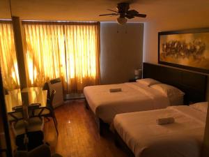 特鲁希略Hotel Las Condes的酒店客房配有两张床和吊扇。