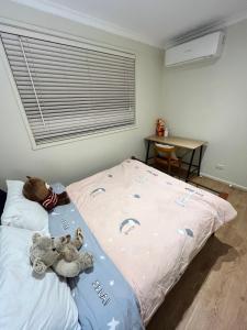 弗兰克斯顿Cosy 3 bedroom family home near beach and shops的卧室里床上有两只填充的动物