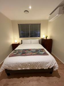 弗兰克斯顿Cosy 3 bedroom family home near beach and shops的一间卧室设有一张大床和一个窗户。