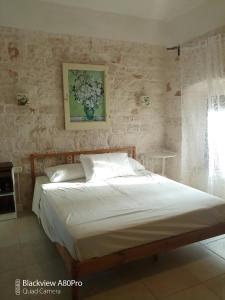 孔韦尔萨诺B & B Monte Adamo的卧室内的一张床铺,墙上有绘画作品