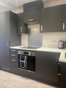 赫默尔亨普斯特德New modern 1 bedroom duplex apartment Hemel Hempstead High Street的厨房配有黑色橱柜和黑色烤箱