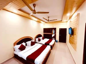 ShamshiHotel Amit的配有电视的酒店客房内的两张床
