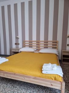 里米尼Beach Hotel Clerice的一间卧室设有两张带黄床单和条纹墙的床。