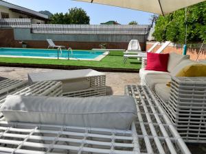 卡瓦德蒂雷尼Villa Morena的一组白色躺椅和一把遮阳伞,位于游泳池旁