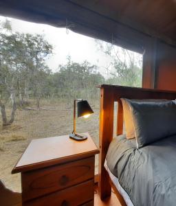 BiboohraWild Nature Lodge, Mareeba Wetlands的一间卧室配有一张床和一张桌子上的台灯