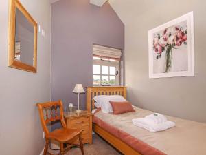 BrantinghamPond View Cottage的一间卧室配有一张床、一张桌子和一把椅子