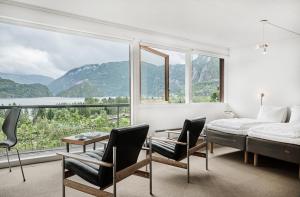 Nesflaten能源酒店的一间卧室配有床和椅子以及大窗户