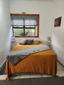 斯泰伦博斯Santika Sunhill Cottage的一间卧室配有一张带橙色毯子和窗户的床。