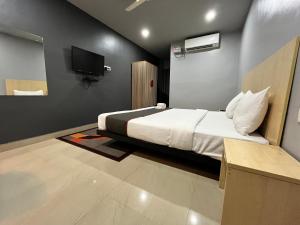 古瓦哈提RJB Grand的卧室配有一张床,墙上配有电视。
