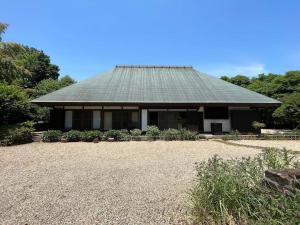 镰仓市甘糟屋敷 Amakasu Yashiki KAMAKURA的一座带绿色屋顶和碎石院的房子