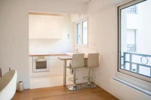 塞纳河畔讷伊Logement entier : appartement • Chez Cecile的厨房配有白色橱柜、桌子和窗户。