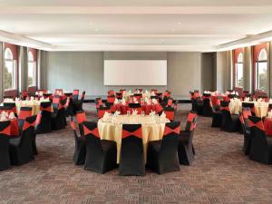 马六甲马六甲宜必思酒店的一间会议室,配有桌椅和屏幕
