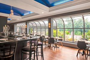 斯坦福德斯坦福希尔顿恒庭旅馆&套房酒店的餐厅设有桌椅和大窗户。