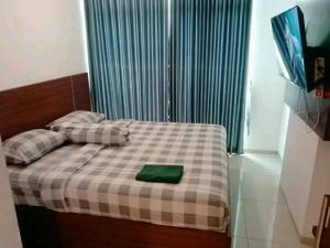 西冷Ilham Apartemen Batch 1的一间卧室配有一张带绿色枕头的床