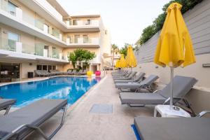 罗希姆诺Dimitrios Beach Hotel Adults Friendly 14 plus的游泳池旁的一排椅子和遮阳伞