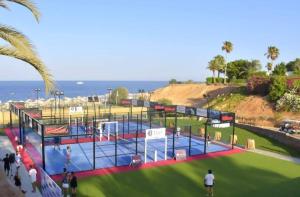 沙姆沙伊赫Suite al Domina Coral Bay , Resort Spa e Casino'的一座以海洋为背景的网球场的 ⁇ 染