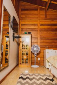多明戈斯马丁斯Pousada Gagno的一间卧室设有木墙、风扇和镜子
