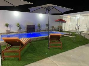 La PuntaDepartamento de playa con piscina en estreno的一个带两把椅子和一张桌子的游泳池以及一把遮阳伞