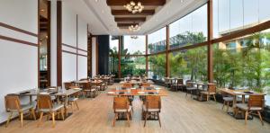 科钦科钦万豪酒店的餐厅设有桌椅和大窗户。