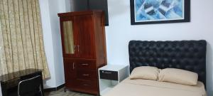 马尔多纳多港Makasai Tambopata 3的一间卧室配有一张带黑色床头板和橱柜的床。