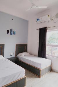 克久拉霍Aarambh Residency的一间卧室设有两张床和窗户。