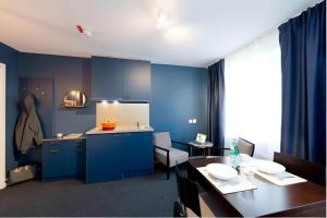 斯德哥尔摩Communia Hotel Residence的厨房配有蓝色橱柜、桌子和用餐室。