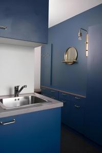 斯德哥尔摩Communia Hotel Residence的蓝色的厨房设有水槽和镜子