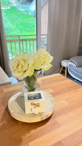 蒂涅Le Petit Chalet Addicted to Paradise的一张带黄花的花瓶,放在桌子上,放一张卡片