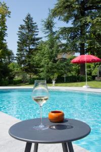 Les MarchesDomaine des Granges Longes的坐在游泳池畔的桌子上喝一杯葡萄酒