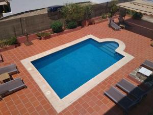 蒙地卡罗Hostal El Pinar的砖砌庭院里的一个大型蓝色游泳池