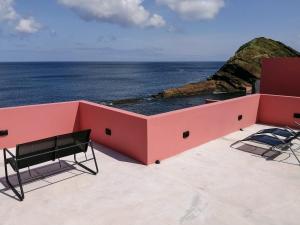圣罗克Terreiro Ocean House - Sea View的一座粉红色的建筑,配有两把椅子,享有海景