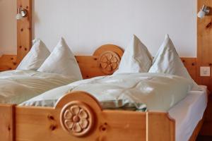 贝特默阿尔卑Hotel Waldhaus的一张带白色床单和枕头的木床